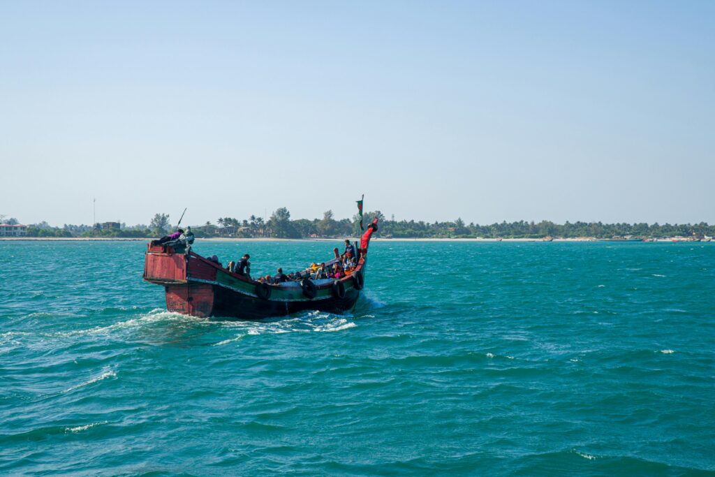 A traditional fishing boat navigates the turquoise waters near a tropical shore.